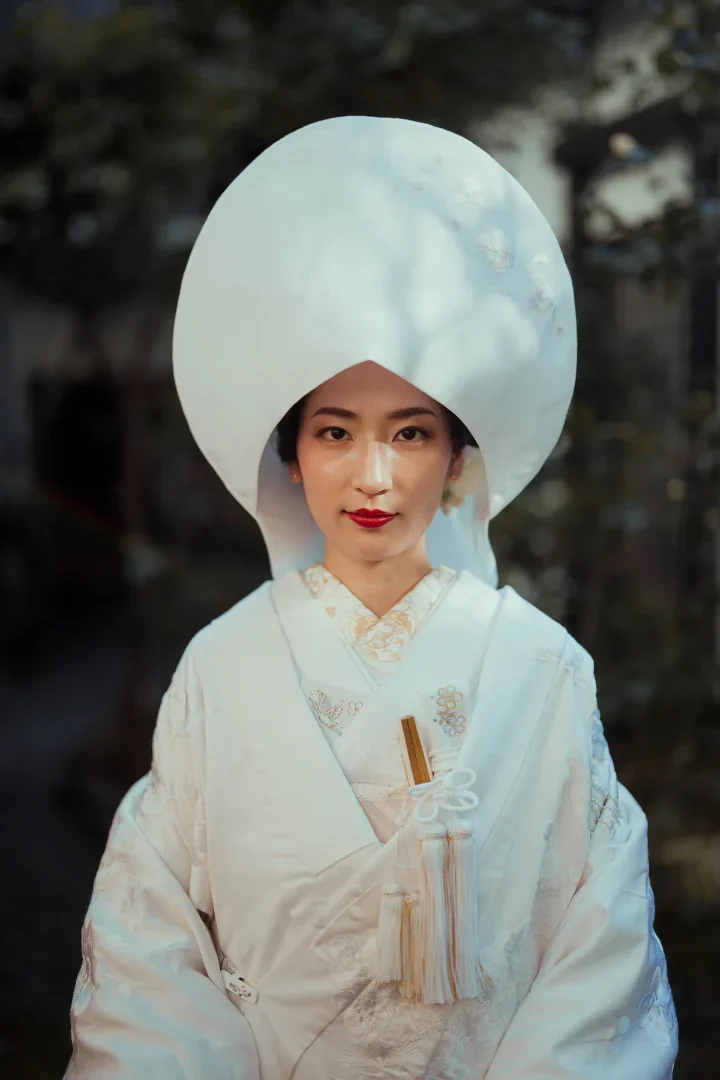 A bride in traditional 'shiro-muku' attire with a 'tsunokakushi' headdress, embodying purity and elegance in a Shinto wedding.