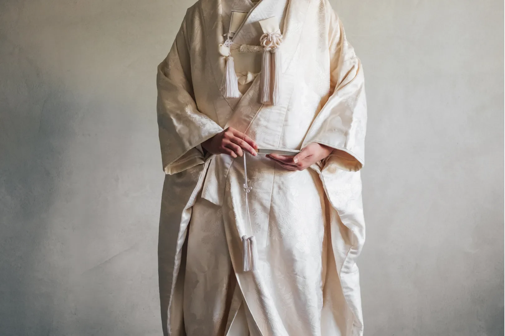 A bride wearing a traditional shiromuku and a groom in a montsuki hakama, standing in front of a Shinto shrine. The attire symbolizes purity and cultural heritage. Traditional Japanese Attire and Modern Wedding Dresses