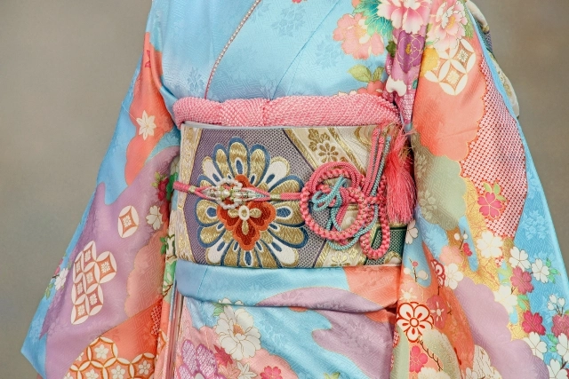 Close-up of a vibrant floral kimono worn during a Shinto wedding ceremony, showcasing intricate patterns and traditional obi belt design.