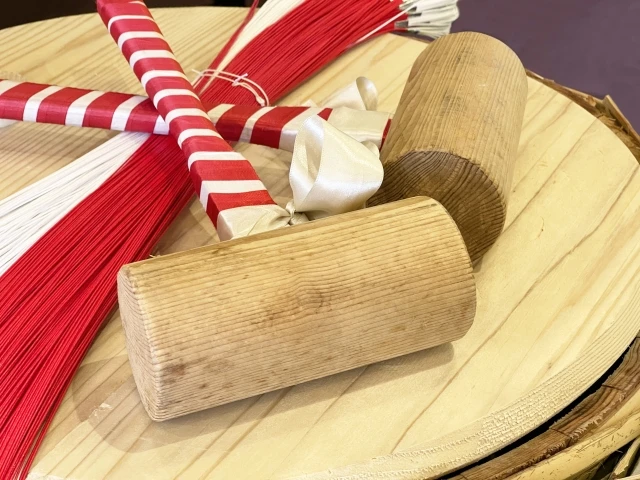 Wooden mallets and red-and-white decorative cords placed on a closed sake barrel, prepared for the Kagamibiraki ceremony, symbolizing celebration and harmony.
