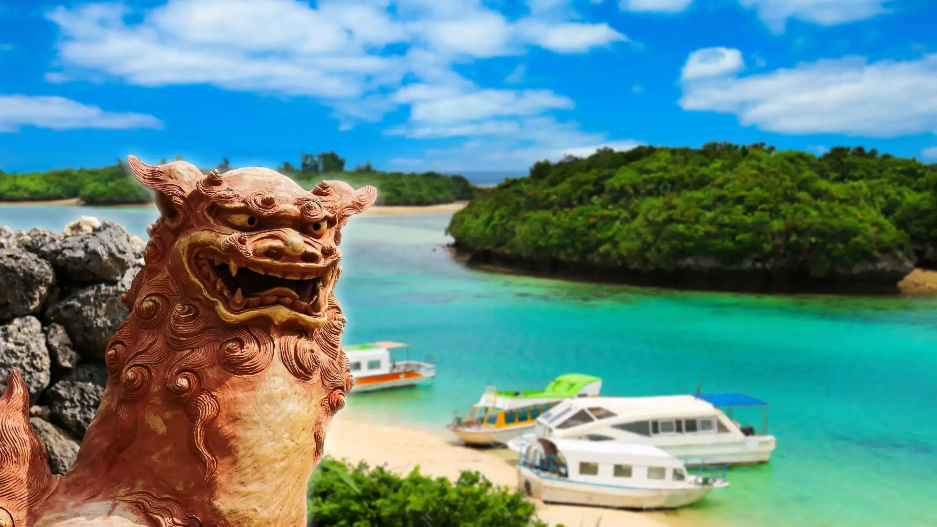 Traditional Okinawan shisa guardian statue overlooking emerald turquoise bay and tour boats in Ishigaki Island, Yaeyama Islands.