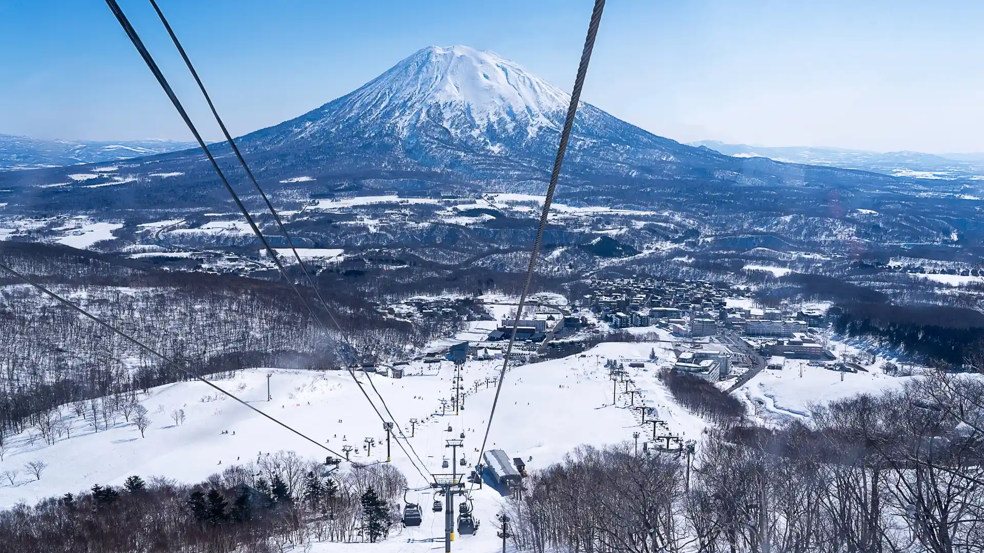 Snowy winter landscape of Niseko with Mount Yotei in the background, ski lifts and slopes in foreground, Hokkaido Japan