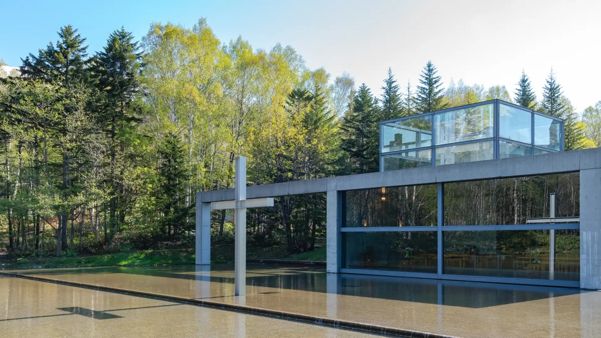 Church on the Water at Tomamu, modern glass chapel with cross reflecting in the pond, surrounded by forest, Hokkaido Japan